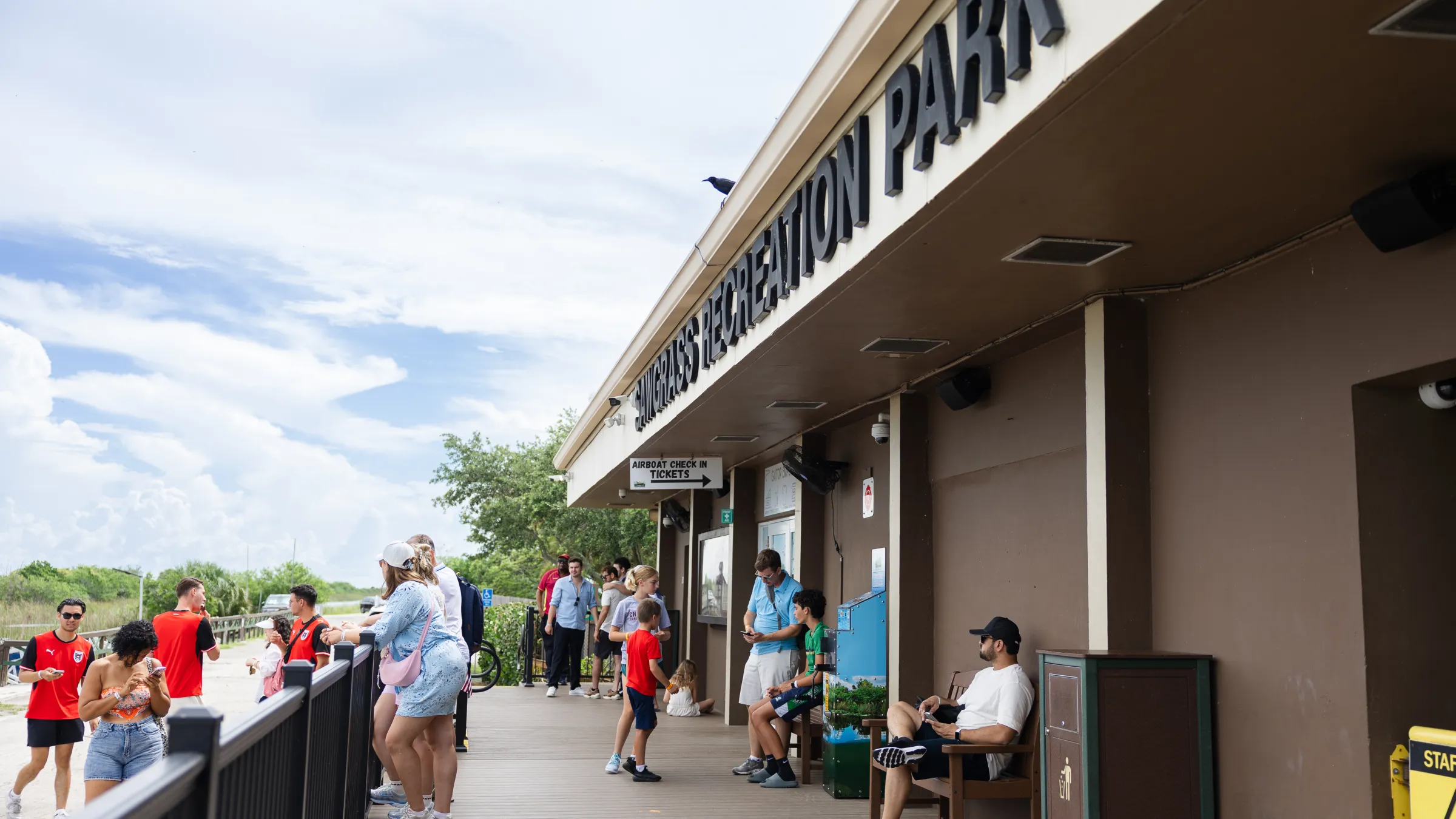People gather outside a building labeled 'Recreation Park' under a cloudy sky.