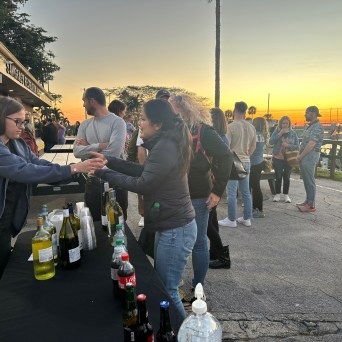 People gathering at an outdoor drink stand during sunset.