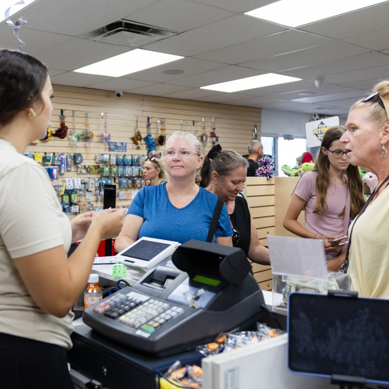 Women in store interacting with staff near the checkout counter.
