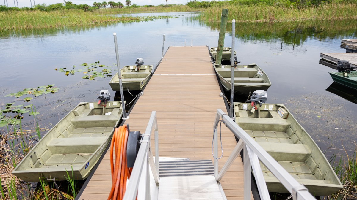 Dock with small boats on a calm lake surrounded by reeds.